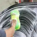 Limpeza de carro com esponja verde e espuma.