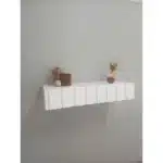 Prateleira com urso de pelúcia e vaso de flores.