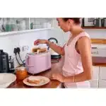 Mulher tostando pão em torradeira rosa