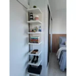 Prateleira vertical moderna com livros e acessórios.