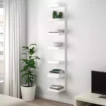 Estante branca com plantas e livros decorativos.