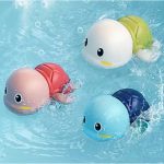 Brinquedo de banho tartaruguinha flutuando na água da banheira com bebê sorrindo